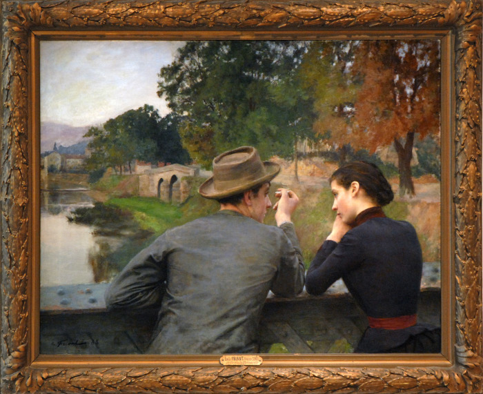 Émile Friant, «Les Amoureux», 1888: ein junger Mann mit Hut und Zigarette und eine junge Frau im dunklen Kleid lehnen nebeneinander am eisernen Geländer einer Fussgängerbrücke über der Meurthe bei Nancy und sprechen miteinander.